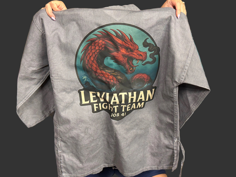 Gray karate shirt with Leviathan Fight Team logo held up in a casual setting